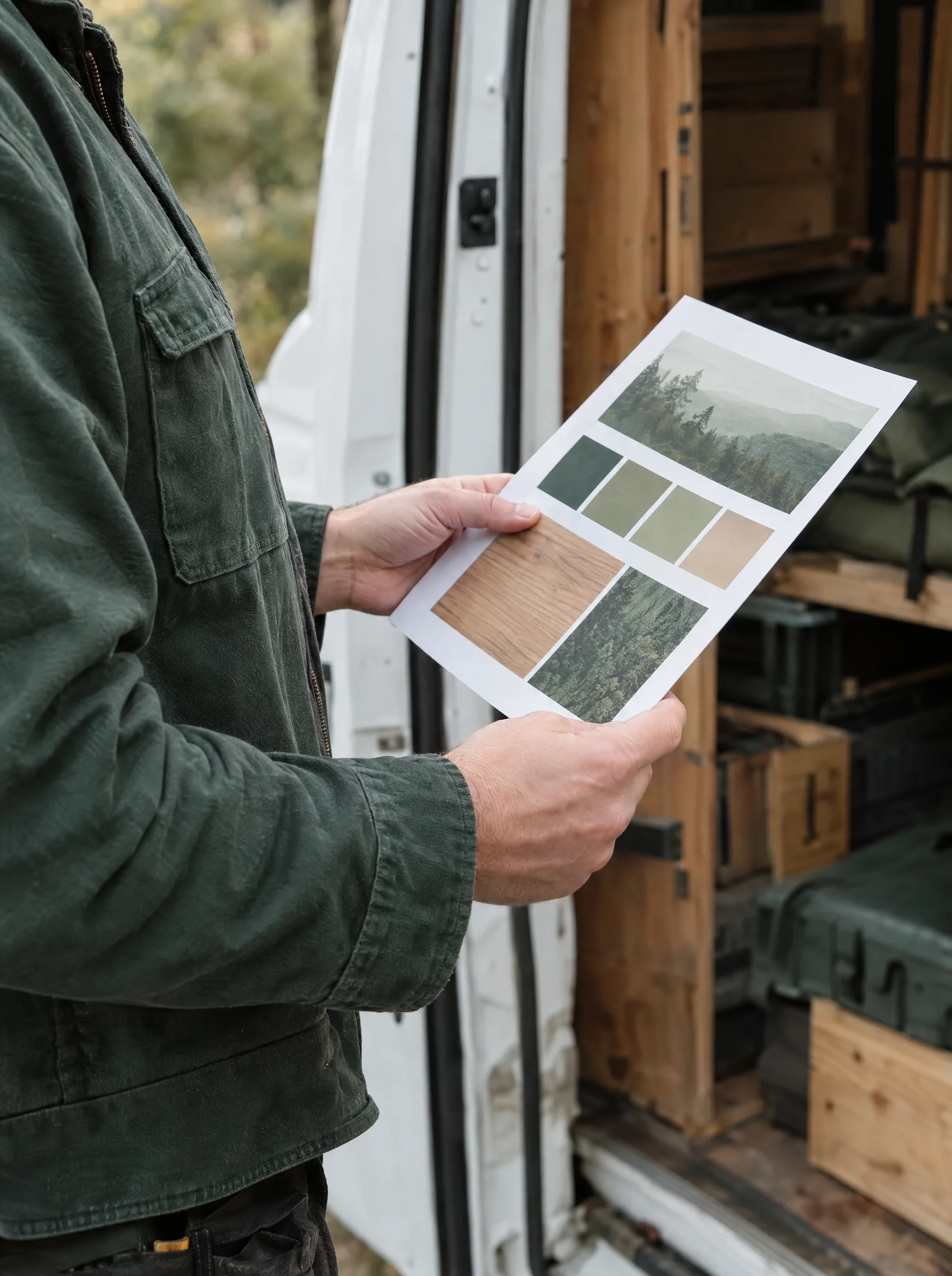 Handwerker an seinem Transporter hält einen ausgedruckten Website-Entwurf in der Hand